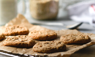 close up of fresh baked oatmeal cookies on baking rack, milk and oats in background 