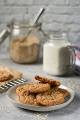 close up of oatmeal cookies on grey plate, milk and oats in background