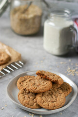 close up of oatmeal cookies on grey plate, milk and oats in background