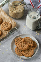 upper view of oatmeal cookies on grey plate with milk and oats