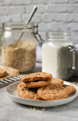 oatmeal cookies on grey plate, milk and oats in background
