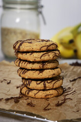 close up of banana oatmeal cookies with chocolate chips, bananas and oats in background