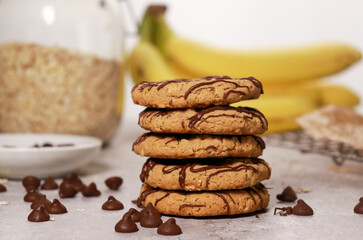 banana oatmeal cookies with chocolate chips, bananas and oats in background