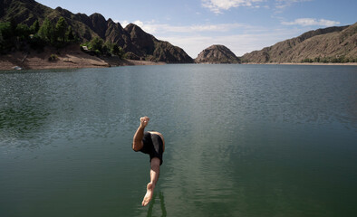 Fototapeta na wymiar Vacations. Man diving into the lake in the mountains, in a summer sunny day.