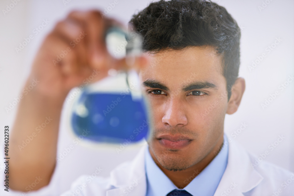 Poster Scrutinizing samples. Shot of a lab technician examining a beaker of blue liquid while standing in a lab.