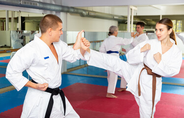 Obraz premium Man and woman in kimono sparring together in gym during karate training