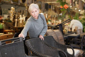 Senior woman selecting new chair in furniture store.