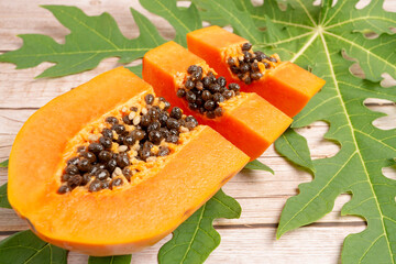 Organic Fresh Ripe Papaya, Thai tropical fruit sliced in pieces over green leaves on wooden table. Good for health.