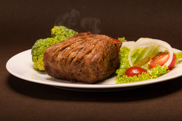 Un plato decorado con hojas verdes y un corte especial de carne a la plancha 