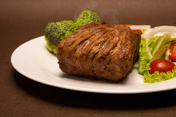 Un pedazo de carne especial vacuno acompañado de brócoli tomate cherry  y lechuga  