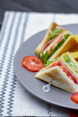 4 club sandwich slices laid out on a gray plate with tomatoes and fries.