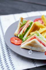 4 club sandwich slices laid out on a gray plate with tomatoes and fries.