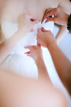 Close up of helpers helping the bride getting ready on her dress