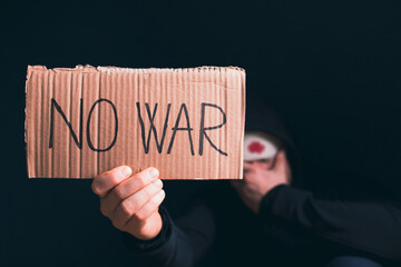 Injured man with No war banner sitting in the dark