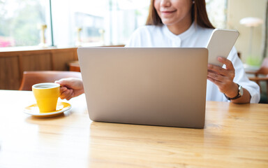 Closeup of a businesswoman holding and using smart phone and laptop computer in office