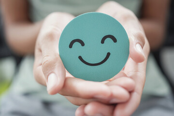 Hands holding green happy smile face paper cut, good feedback rating,think positive, customer review, assessment, child wellness,world mental health day, Compliment Day - 496033508