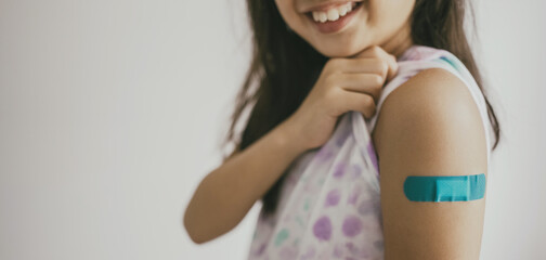 Young preteen girl showing her arm with bandage after got vaccinated or inoculation, child...