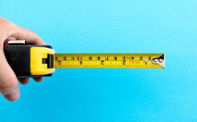 Hand holding tape measuring on blue background