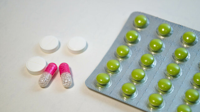 Green tablets in a blister, and next to them lie red and white