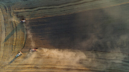 The harvesters harvest grain in a wheat field. Wonderful summer rural landscape, view from the drone.