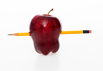 Yellow pencil through an apple on white background