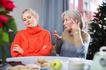 Mature woman quarrels with her adult daughter, who came to visit her before Christmas, scolding her