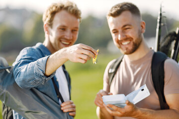 Two men talking and carrying fishing equipment outdoors