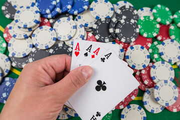 game of poker, the player holds cards in his hand on a green poker table.
