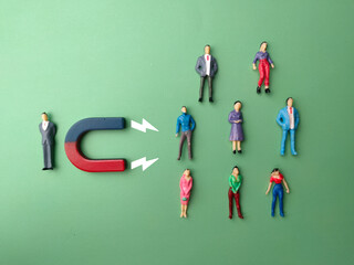 Top view miniature businessman attracts people using magnet. Business concept.