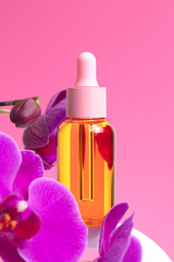 Obraz na płótnie Canvas Mock-up of glass bottle on pink background. Pink orchid flowers are located next to bubble, with oil. Concept of skin care, spa treatments, natural cosmetics.