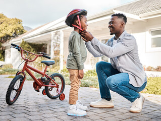 You should be safe while having fun. Shot of a father adjusting a safety helmet on his son while riding a bicycle outdoors. - Powered by Adobe