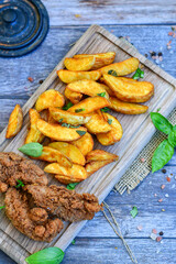 
 Crispy  deep fried   Chicken    strips and Wedges potato. Breaded  with cornflakes chicken  breast fillets  with chilly peppers and fresh   basil on wooden rustic background