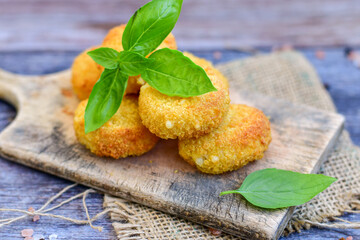 Vegetarian Cheese oven baked Croquette  with  fresh basil on Wooden background. Yellow cheese nuggets