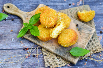 Vegetarian Cheese oven baked Croquette  with  fresh basil on Wooden background. Yellow cheese nuggets