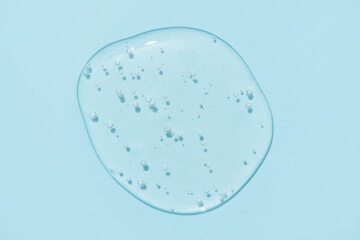Drop of transparent cosmetic textured gel on blue background with bubbles. Copy space. Bath gel...