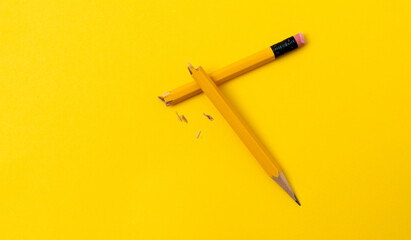 Broken pencil on yellow background