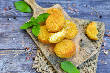 Vegetarian Cheese oven baked Croquette  with  fresh basil on Wooden background. Yellow cheese nuggets