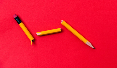 Broken pencil on red background