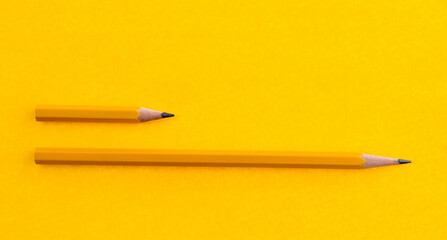 Long and short pencils on yellow background