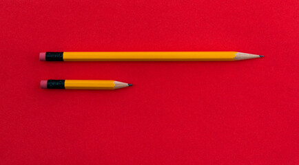 Long and short pencils on red background