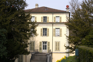 Parc de Mon Repos with yellow villa at City of Lausanne on a blue and cloudy spring day. Photo taken March 18th, 2022, Lausanne, Switzerland.