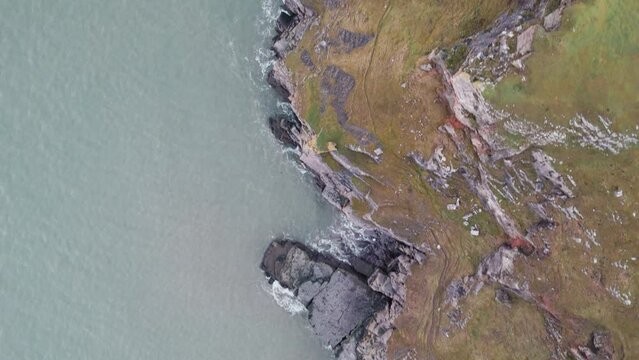 AERIAL: Top down fly along grass covered coastal cliffs, Rhossili Gower, 4k Drone