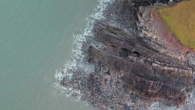 AERIAL: Top down fly along jagged rock coastline, Rhossili Gower, 4k Drone
