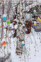 Snow-covered woolen ornaments hang on tree branches close-up.