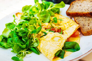 Tasty homemade omelette with fresh salmon served with lettuce on top in white ceramic vintage plate
