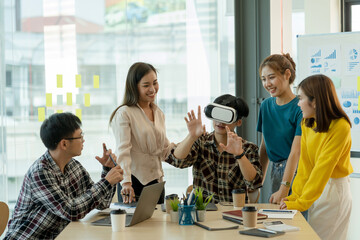 Group of young Asian business people using virtual reality glasses during meeting testing virtual reality headset and exchange project ideas shared to improve the visual experience.