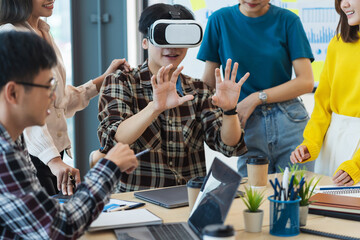 Group of young Asian business people using virtual reality glasses during meeting testing virtual reality headset and exchange project ideas shared to improve the visual experience.