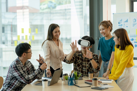 Group of young Asian business people using virtual reality glasses during meeting testing virtual reality headset and exchange project ideas shared to improve the visual experience. - Powered by Adobe