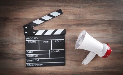 Movie clapper and megaphone on the wooden table.
