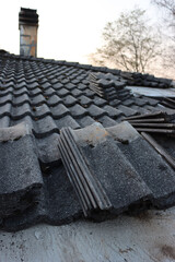 Removing Gray cement roofing tiles damaged by weather on top of a house in Italy